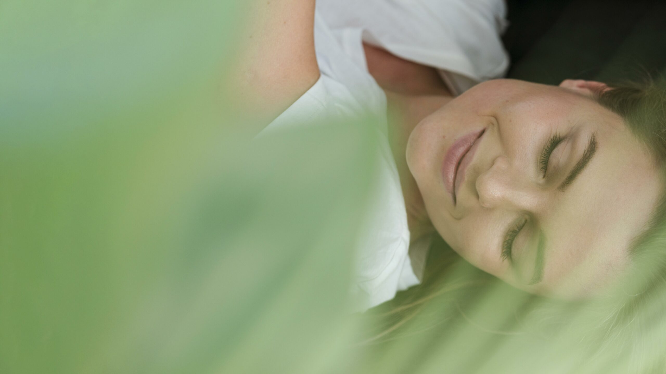 close-up-woman-with-closed-eyes-blurred-plant